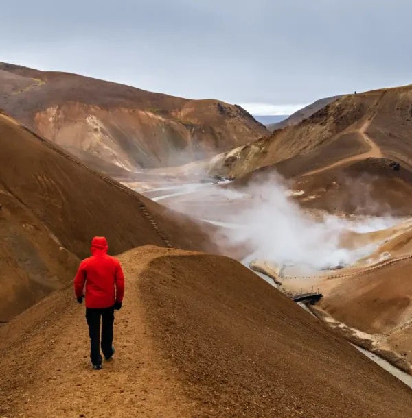 shot-man-red-coat-walking-through-hills-highland-region-iceland